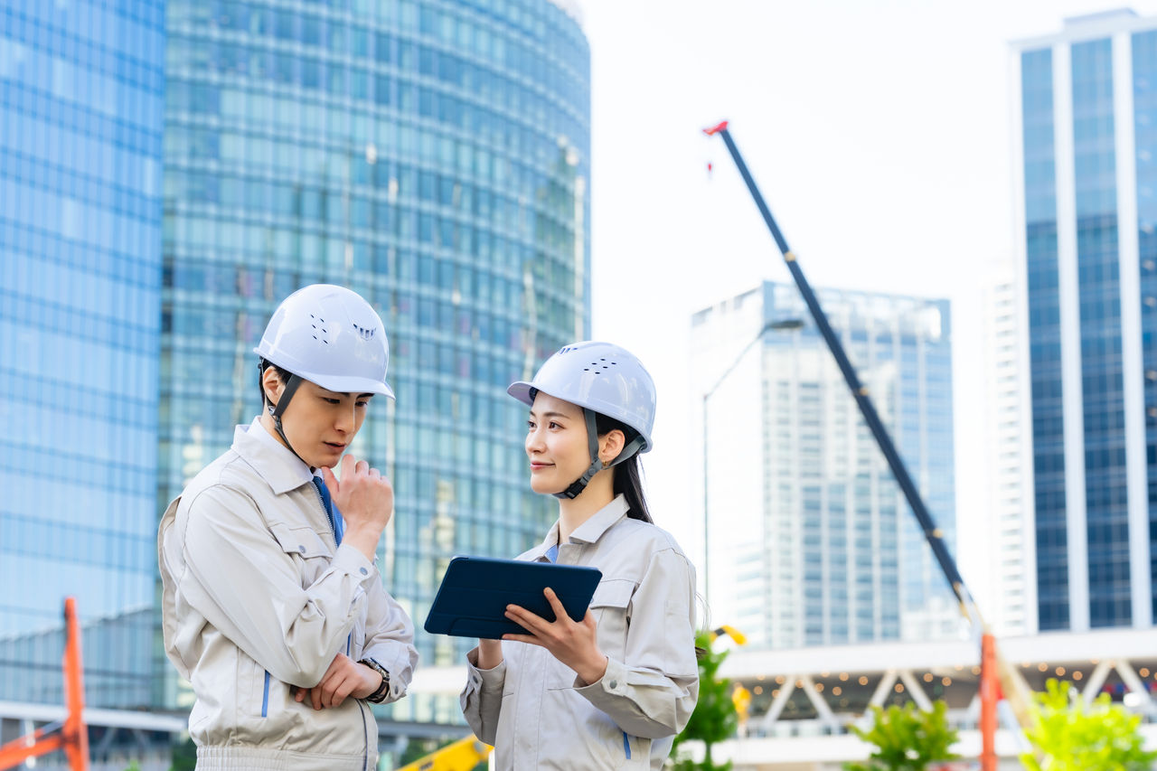 建設、工事、現場、相談、設計、エンジニア、作業員、タブレット、DX、IT、ビジネス、ゼネコン、土木、デベロッパー、クレーン、重機、建築、開発、仕事、計画、都市、都会、ビル、建物、打ち合わせ、会議、ミーティング、屋外、技術者、作業服、ヘルメット、安全、防災、監督、高層ビル、デジタルトランスフォーメーション、ICT、IIoT、テック、テクノロジー、住宅、不動産、男性、女性、日本人、チームワーク、協力、