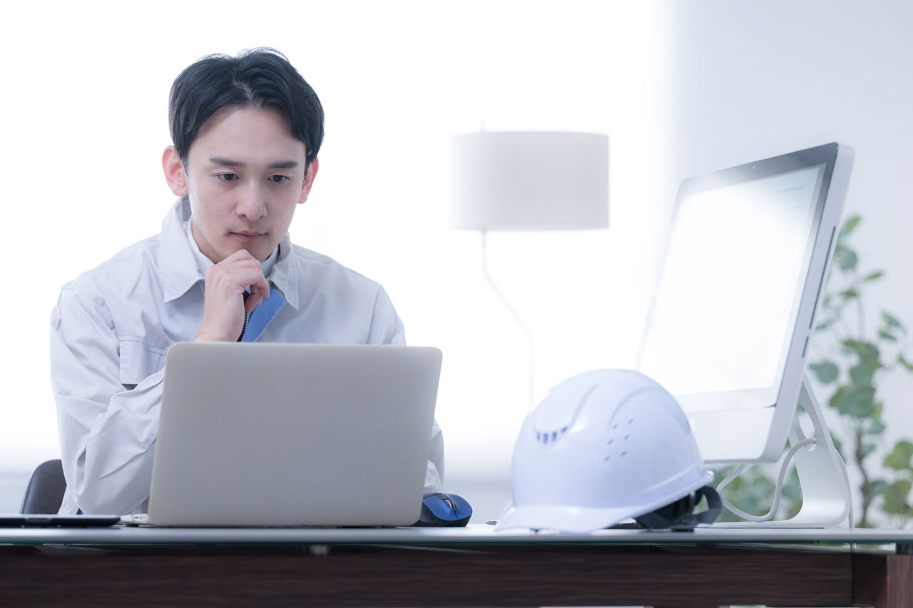 現場事務所で考える作業着の作業員