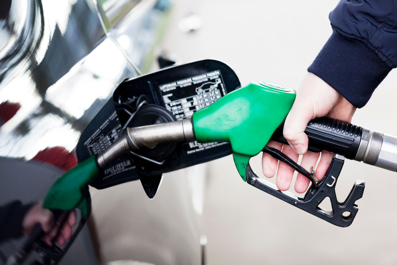 Pumping gas at gas pump. Closeup of man pumping gasoline fuel in
