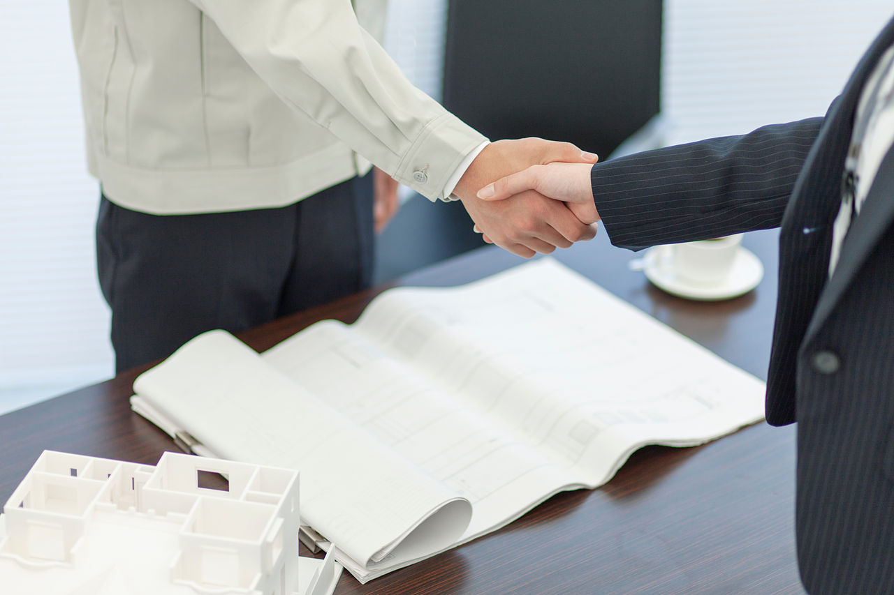 握手をする作業着姿の男性とビジネスウーマン 