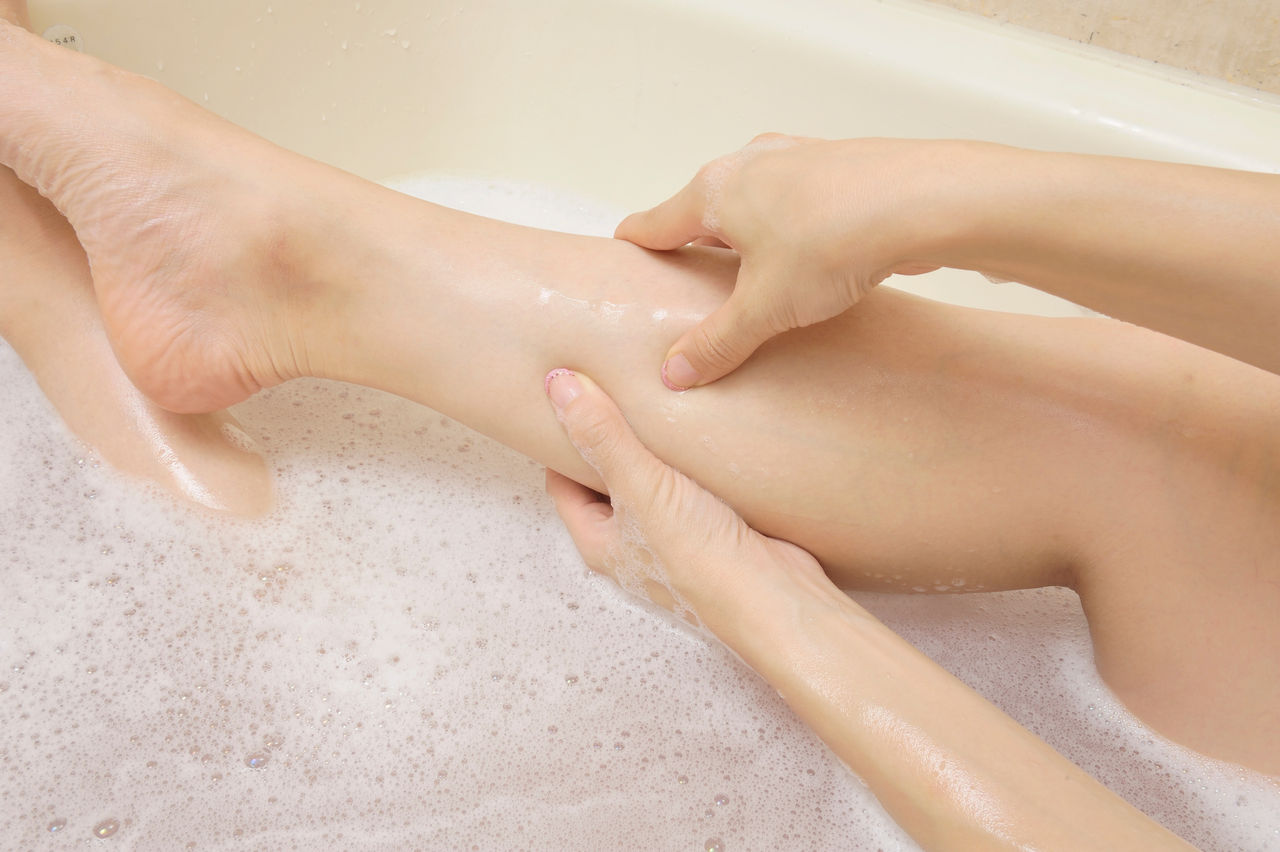 お風呂で脚を揉む女性の手