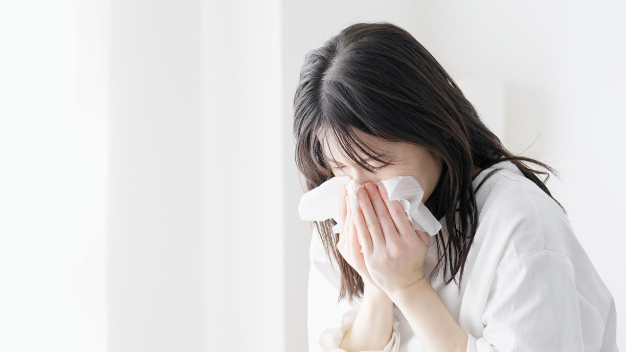 Woman blowing her nose in the room