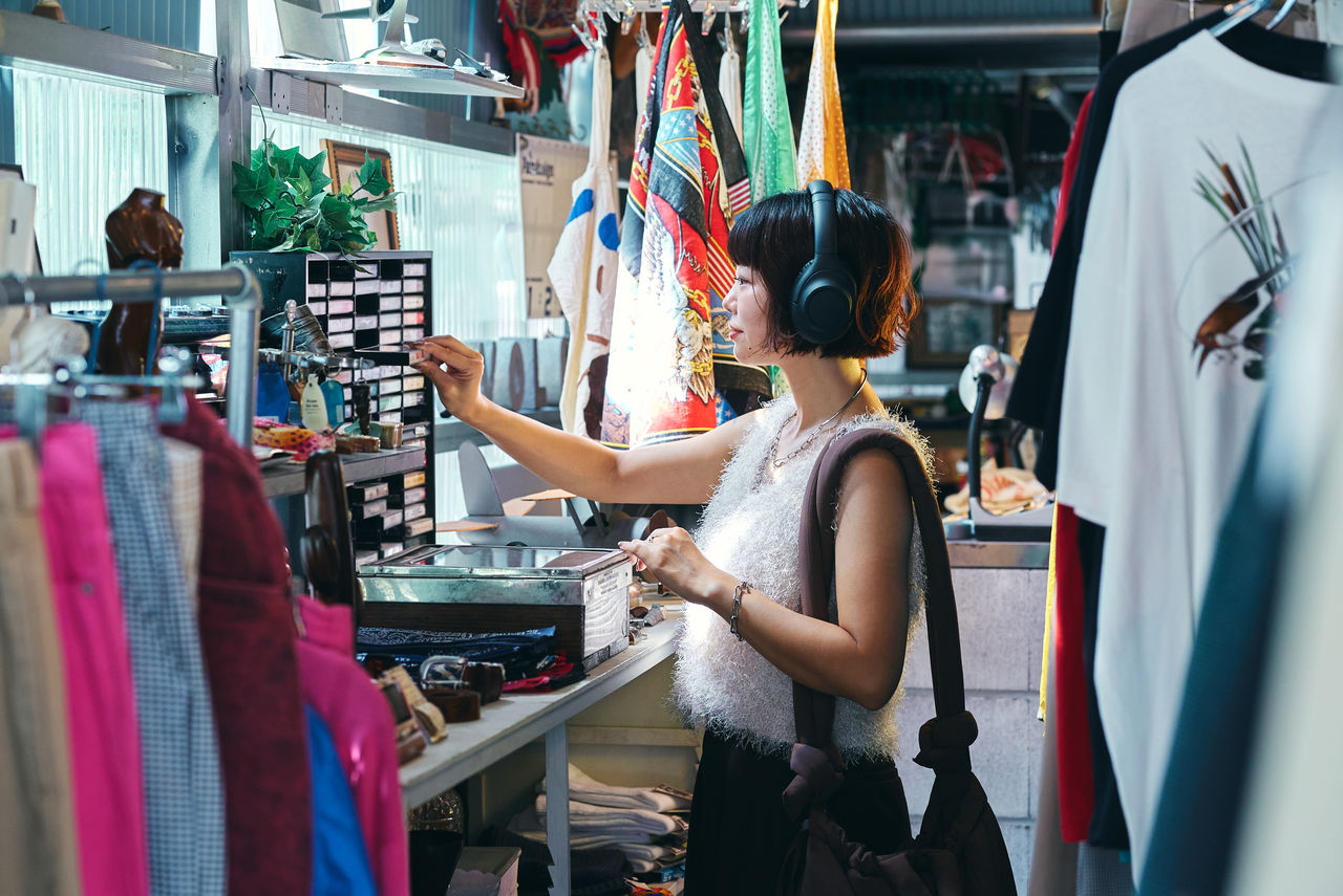 レトロなアイテムが並ぶビンテージショップで買い物をする若い女性